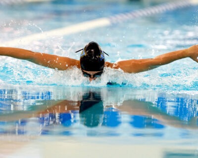 Swimmer swimming the butterfly at SwimRVA. Swimmer has black swim cap and goggles.