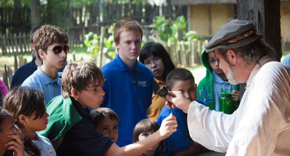 Man in historic outfit dating back to 1600s showing a group of children an artifact at Henricus Historical Park